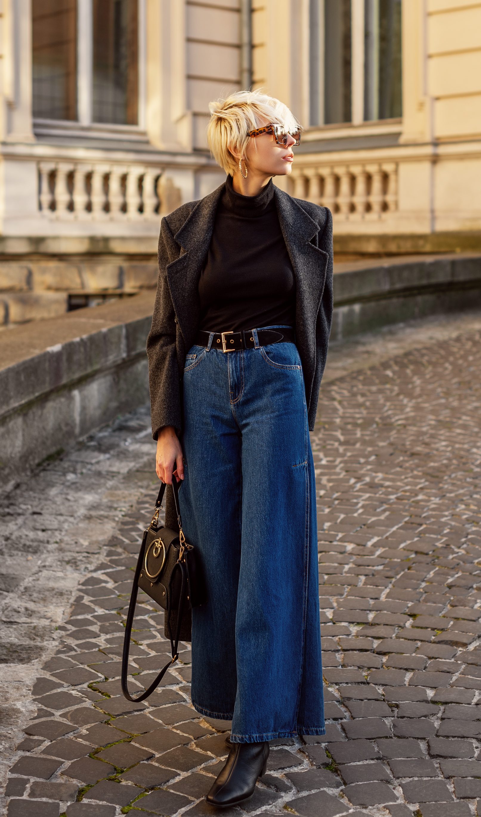 Luxury grey coat, sunglasses, wide leg blue jeans, ankle boots styled with a leather bag