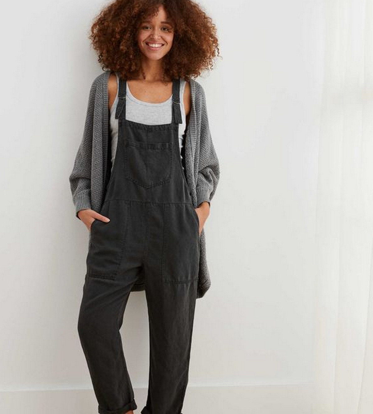 A White Tank Top And Grey Cardigan With Black Overalls
