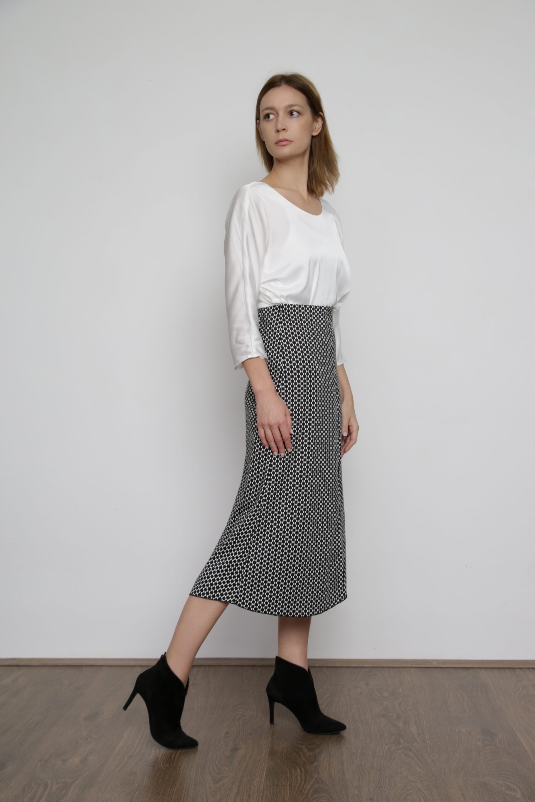 A White Silk Blouse With A Black Midi Skirt And Black Ankle Boots