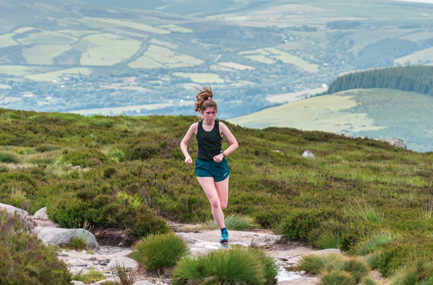 Trail runner wearing Nike shorts with a sports singlet running in Wicklow mountains