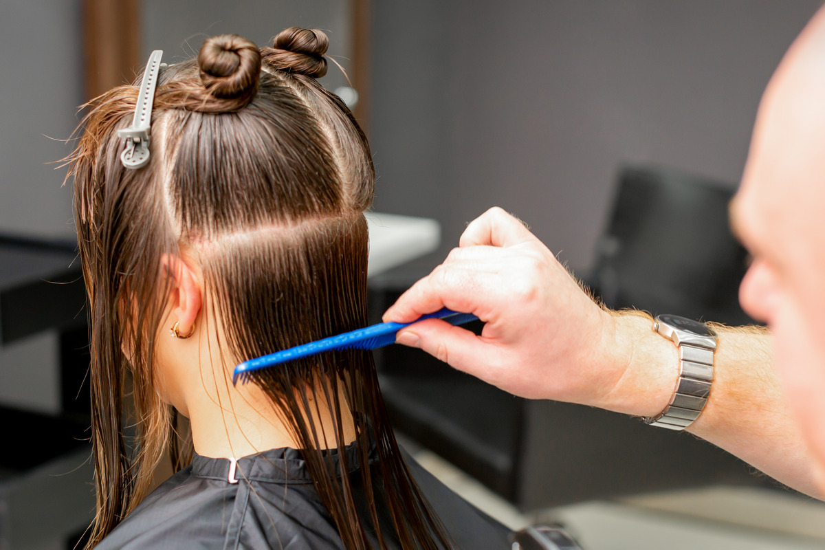 A hairdresser combing wet hair divides into sections in a hair salon
