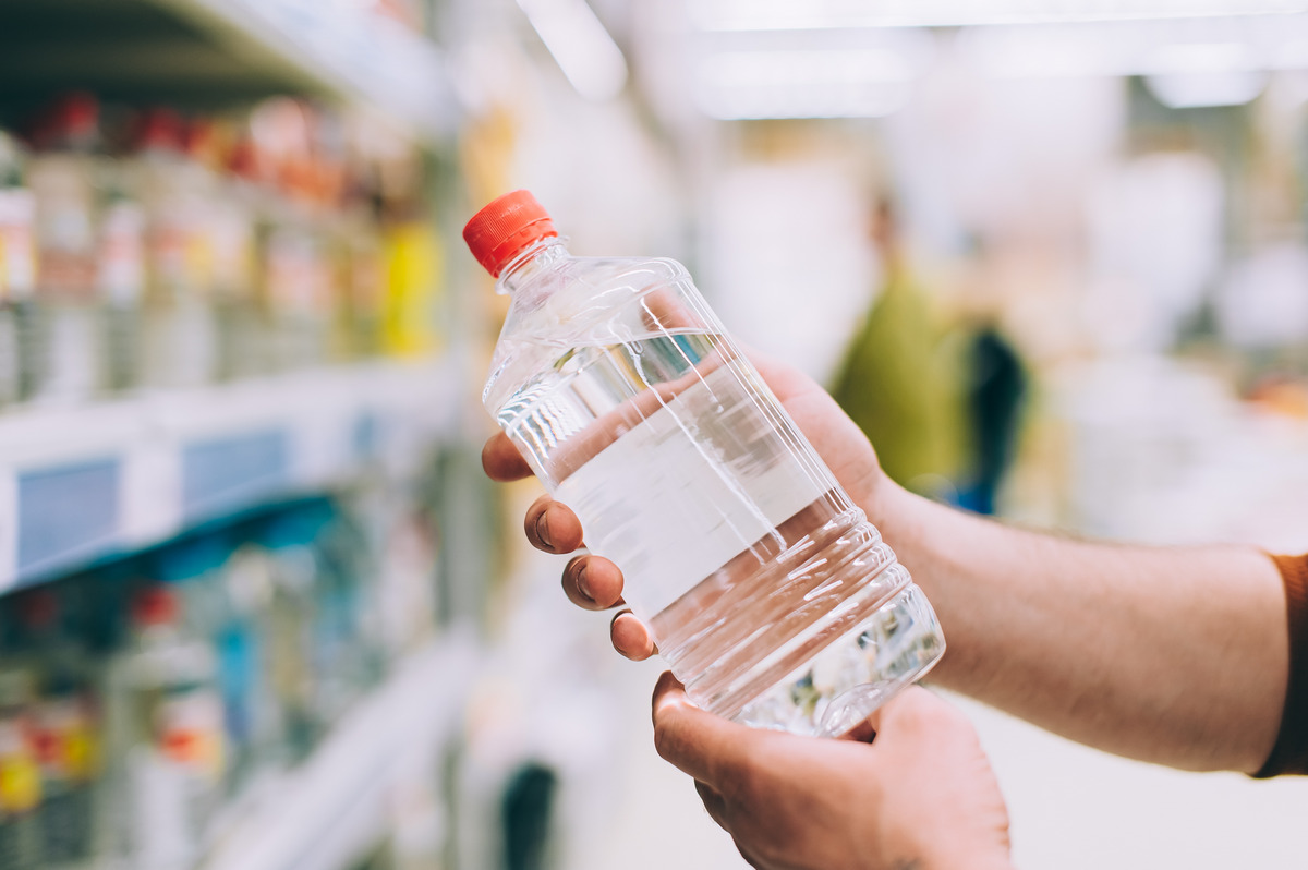 A man in a hardware store holds a bottle of solvent