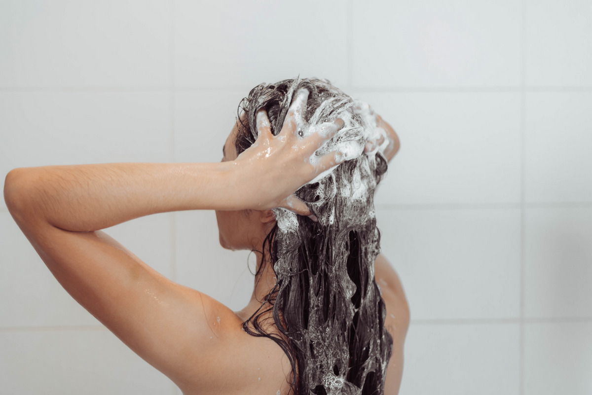 A young woman is cleansing her hair while showering