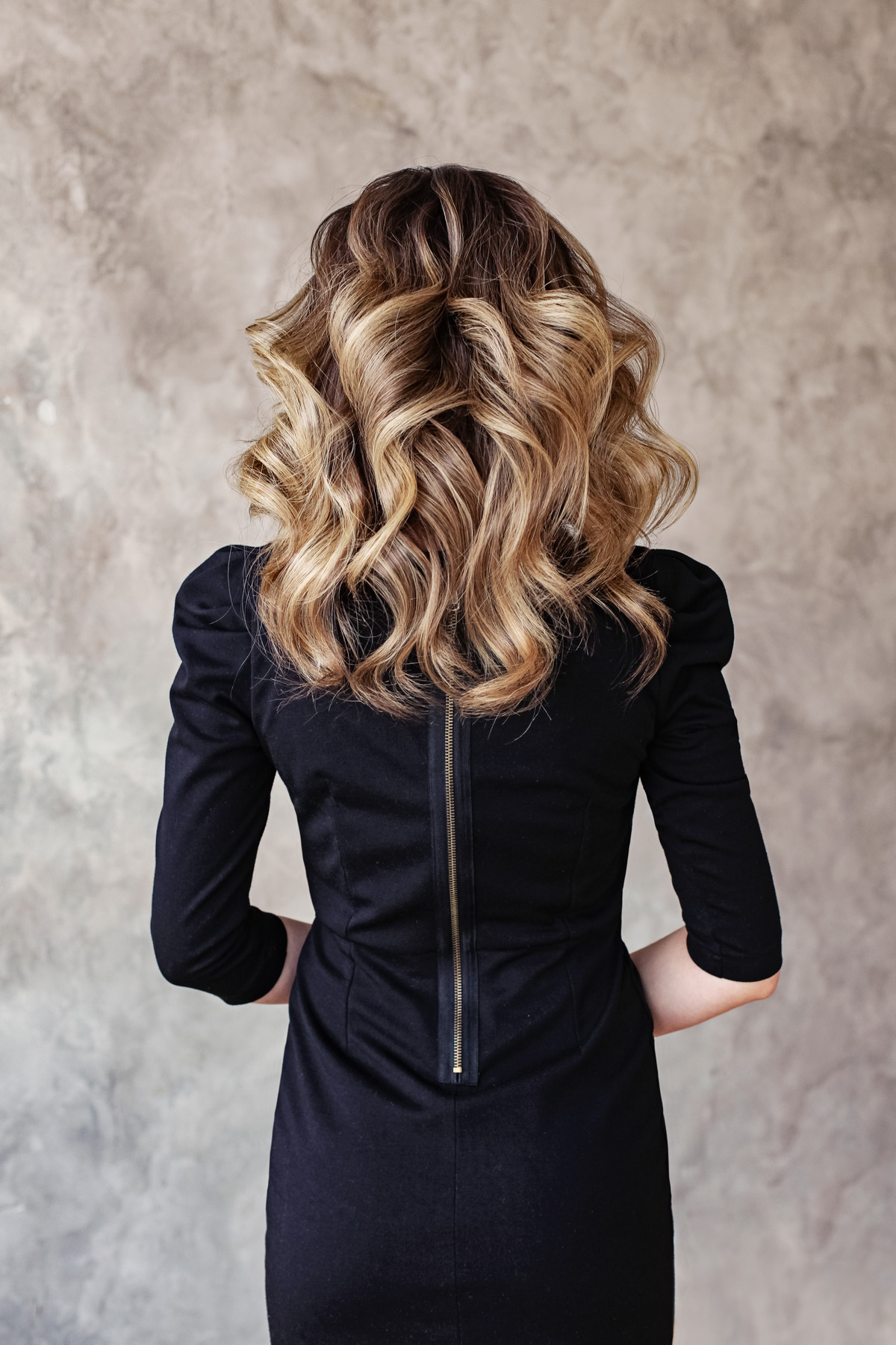 Beautiful woman back with curly hairdo on gray background