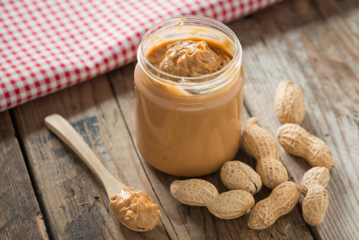 Creamy and smooth peanut butter in a jar on a wooden table