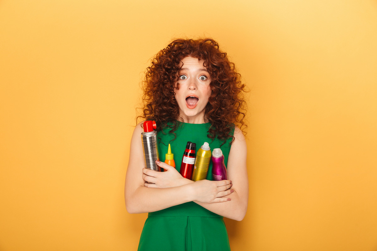 Curly red hair woman holding a lot of hair care products