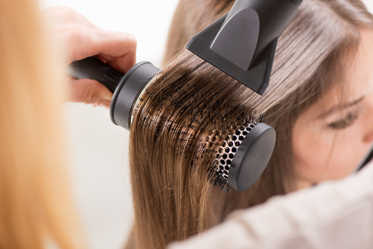 Drying the long hair by using a hair dryer and round brush