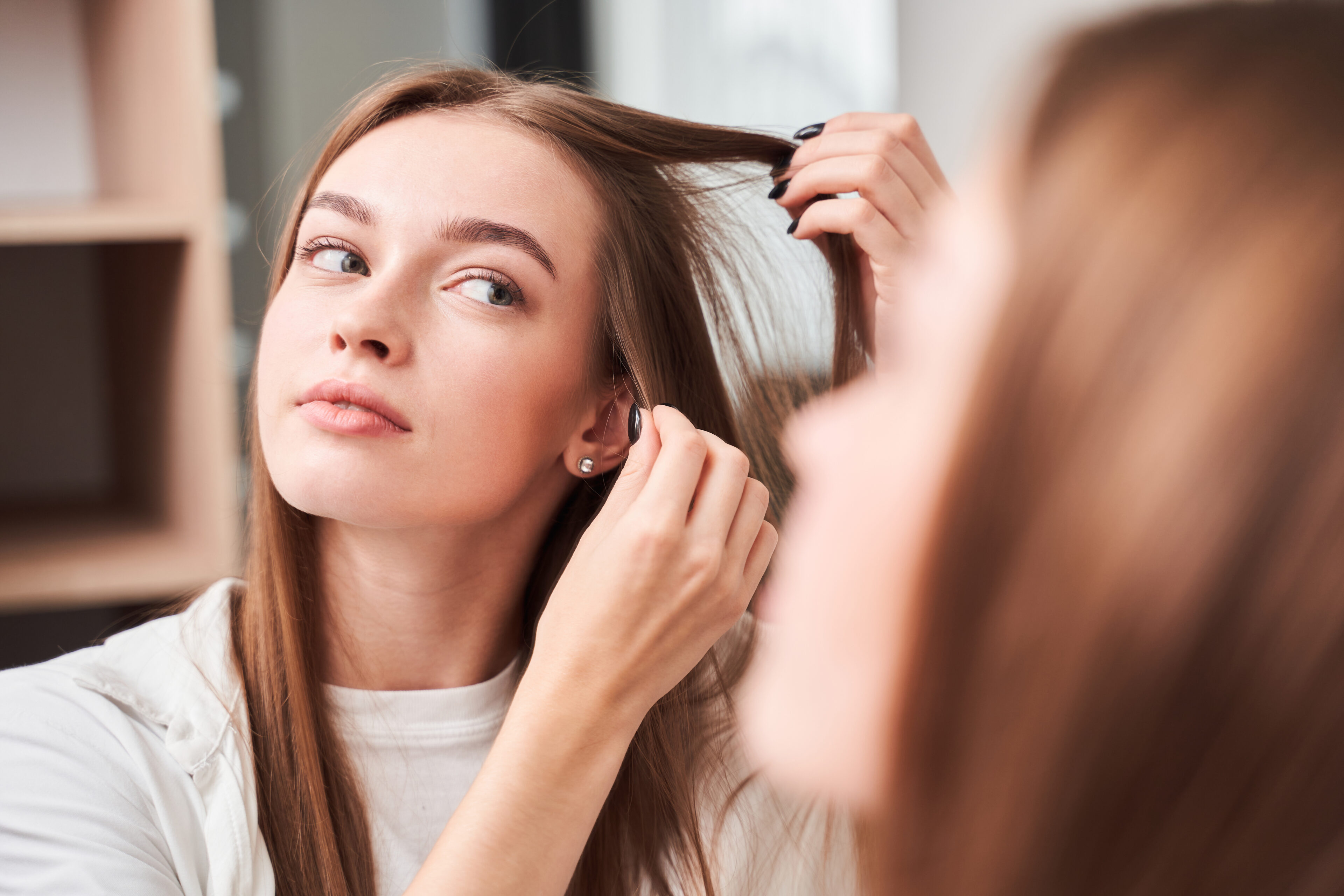 A girl’s sectioning her hair before cutting bangs