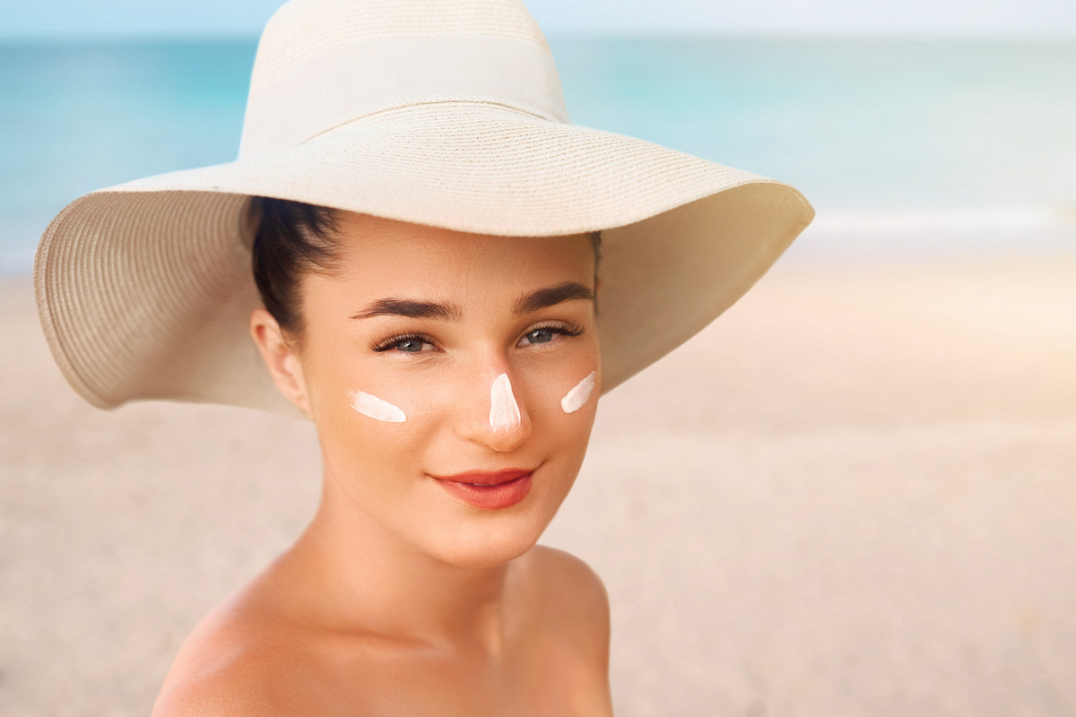 Female in hat smear moisturizing lotion on skin