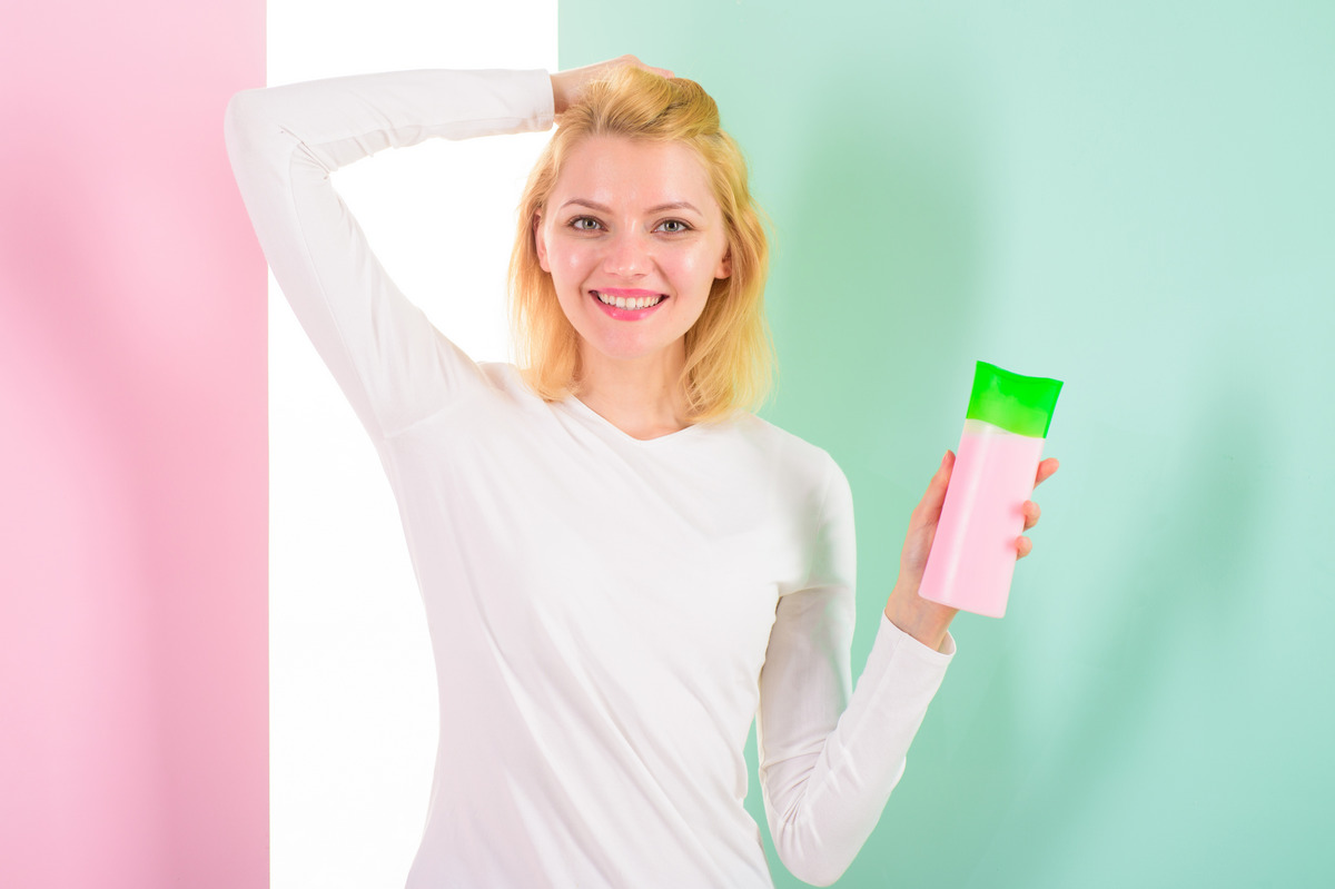 Girl blonde holds a shampoo bottle
