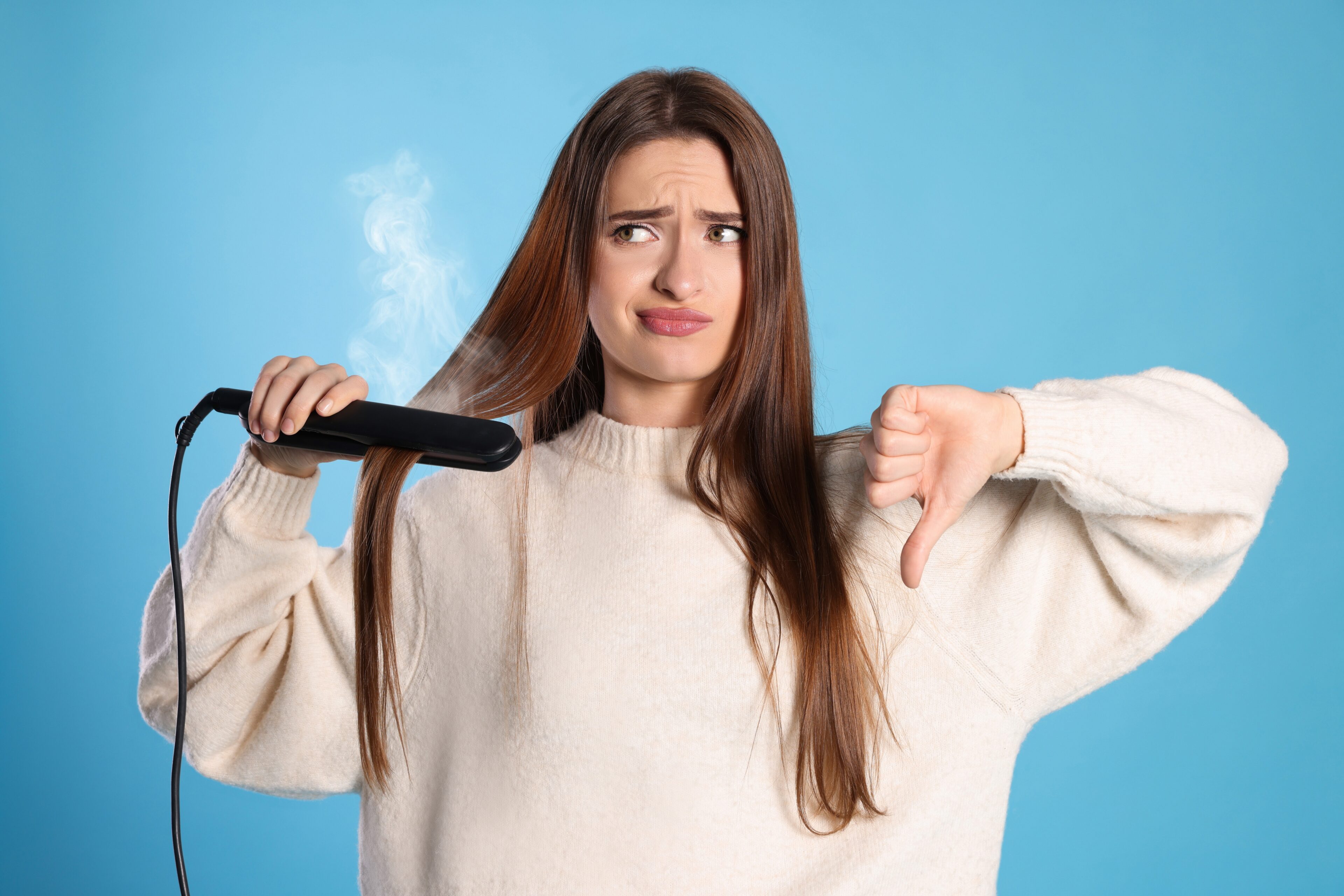 Upset young woman with a flattening iron