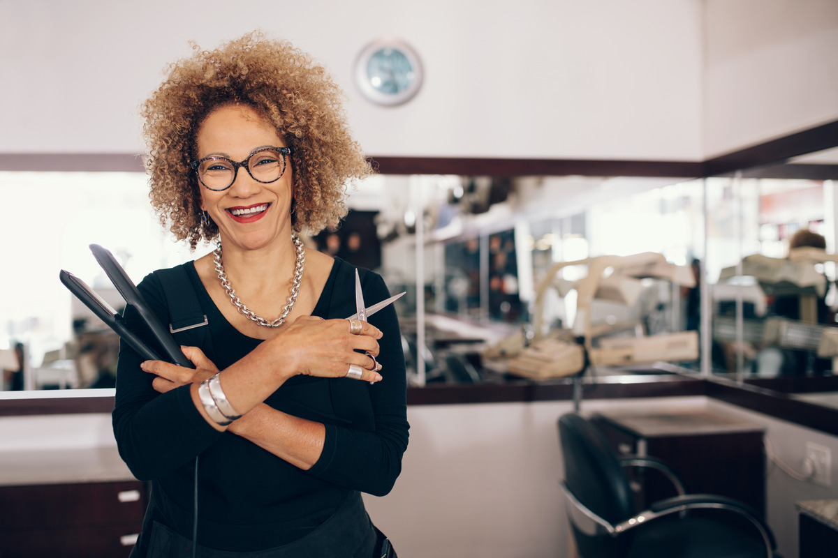 Professional hair stylist holding a straightener and scissors