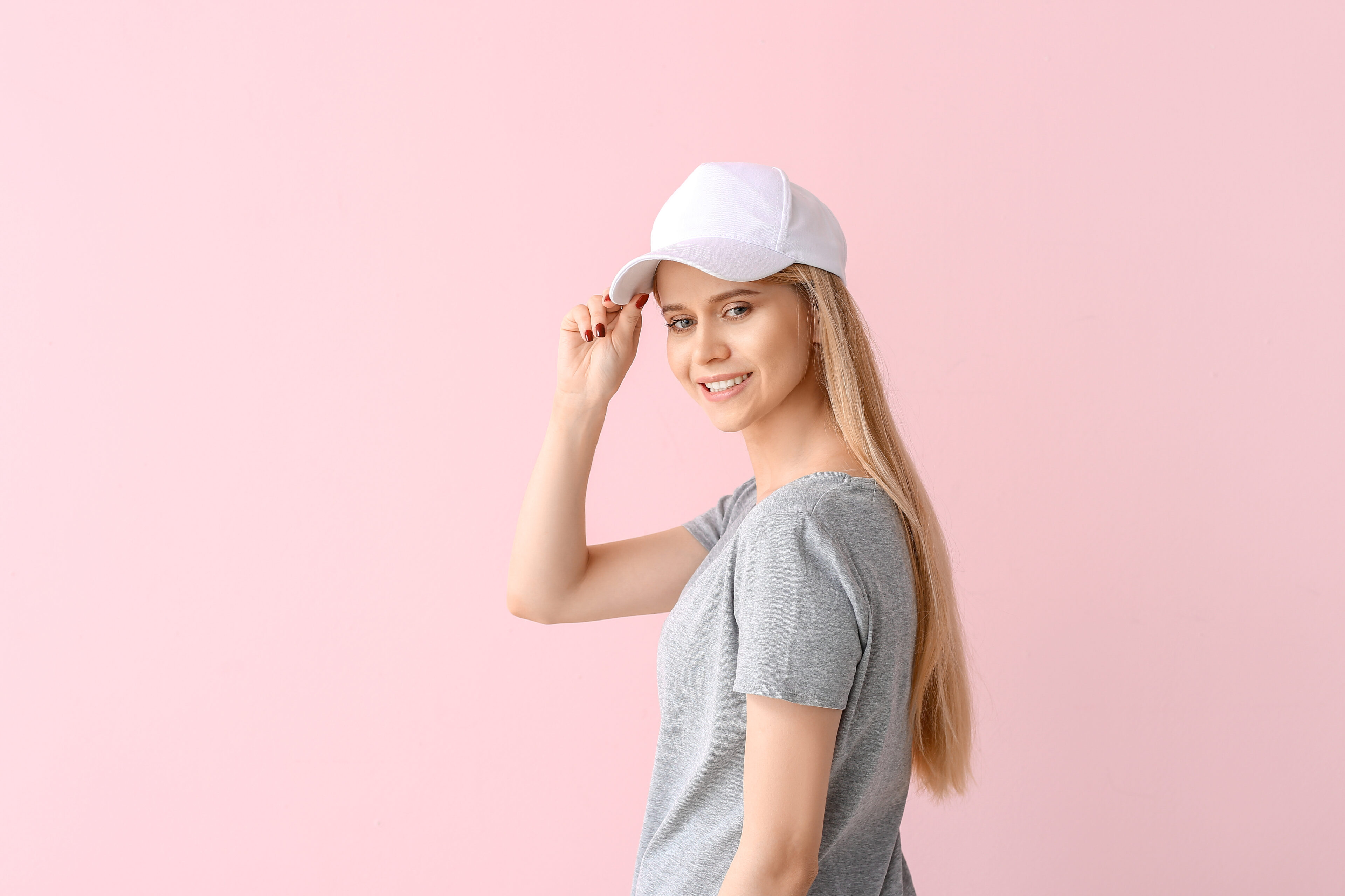 Beautiful young woman in stylish cap on color background