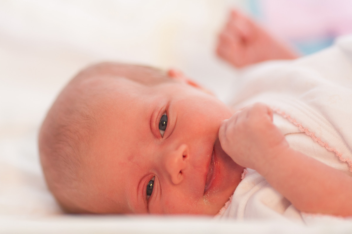 The cute baby with lanugo hair is smilingÂ