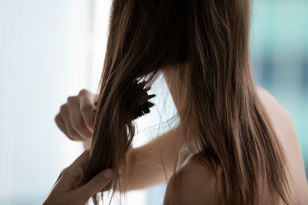 The woman uses a hairbrush comb to detangle from the ends