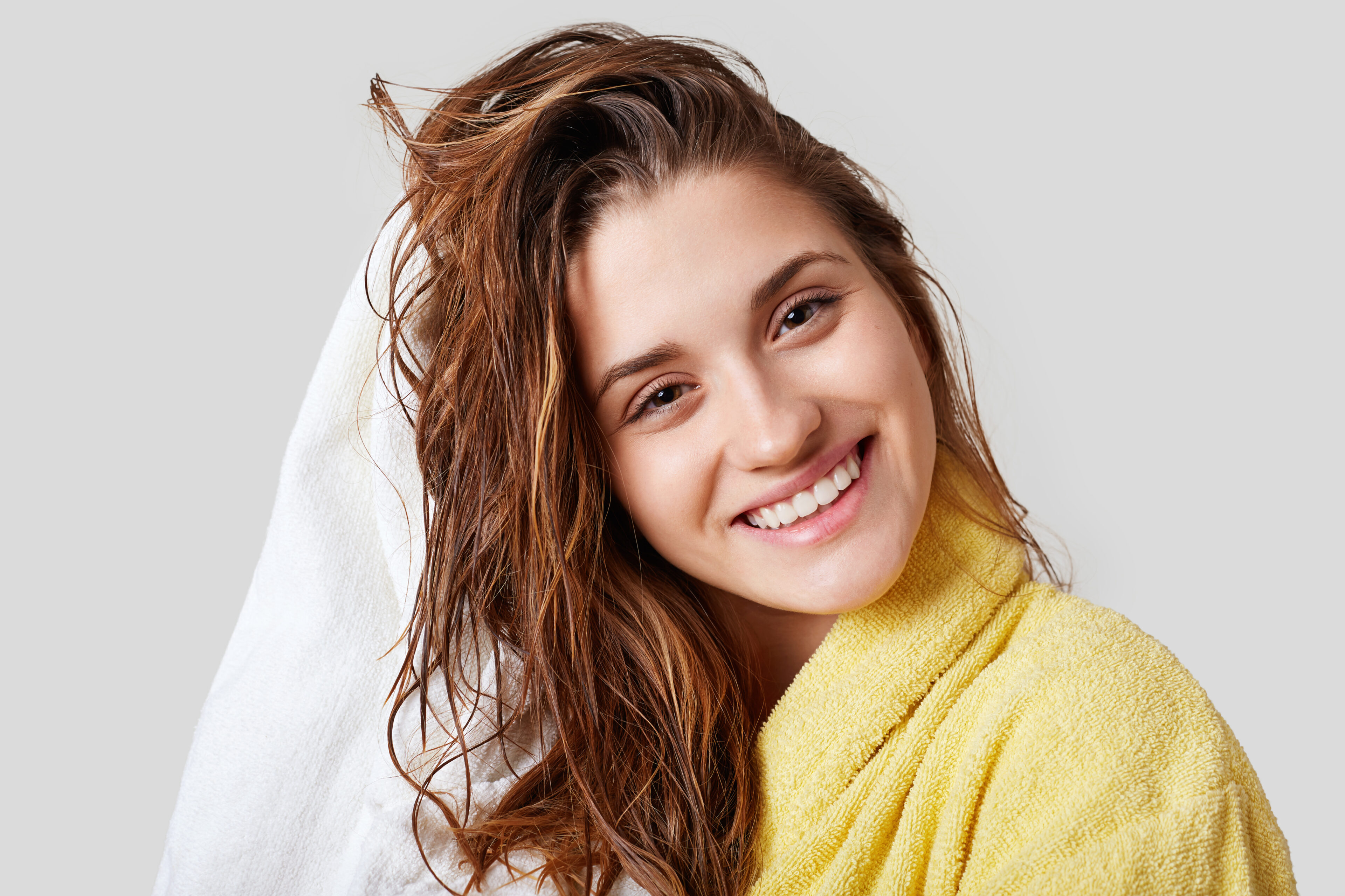 Female with wet hair, showering, drying her head with a towel, satisfied after bathing