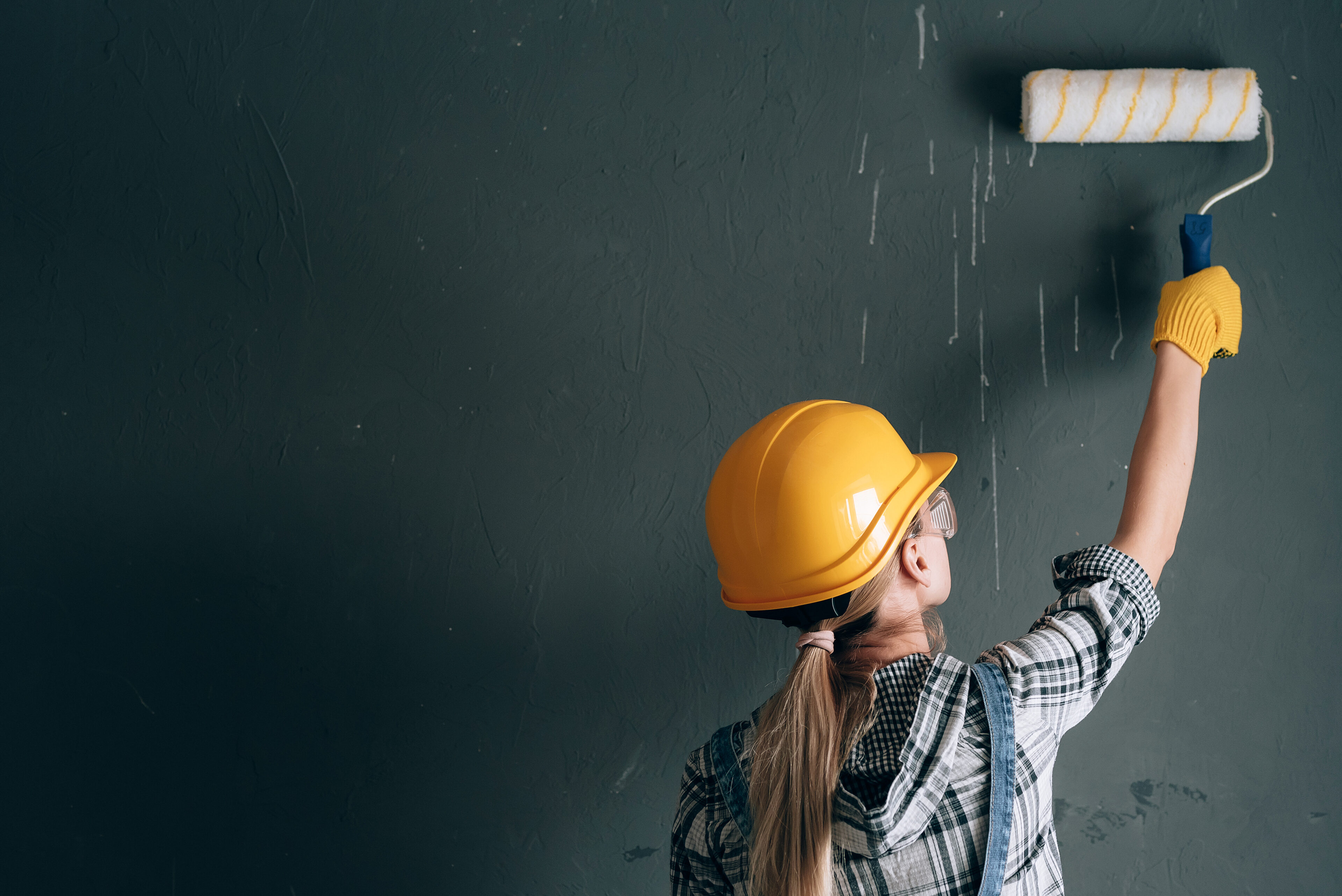 Girl wearing a protective hat and holding a wall paint roller