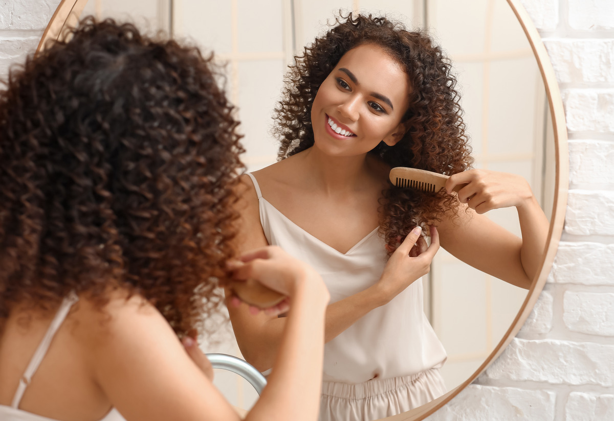 Woman combing her hair near mirror in the bathroom