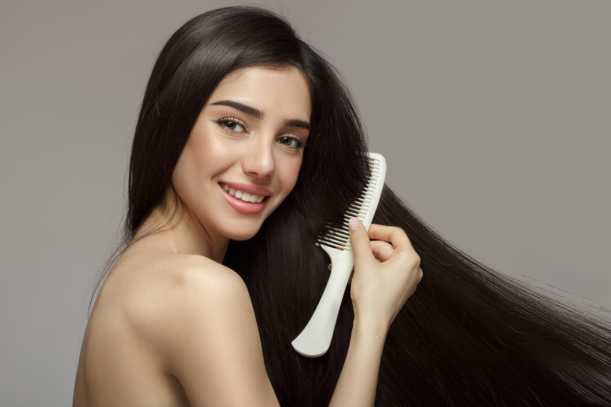 Woman uses hairbrush to comb do morning routine hairs 