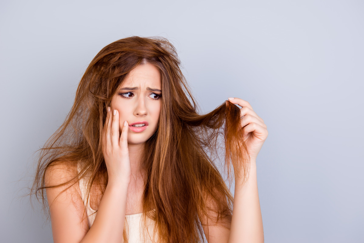 Young girl looking at her damaged hair