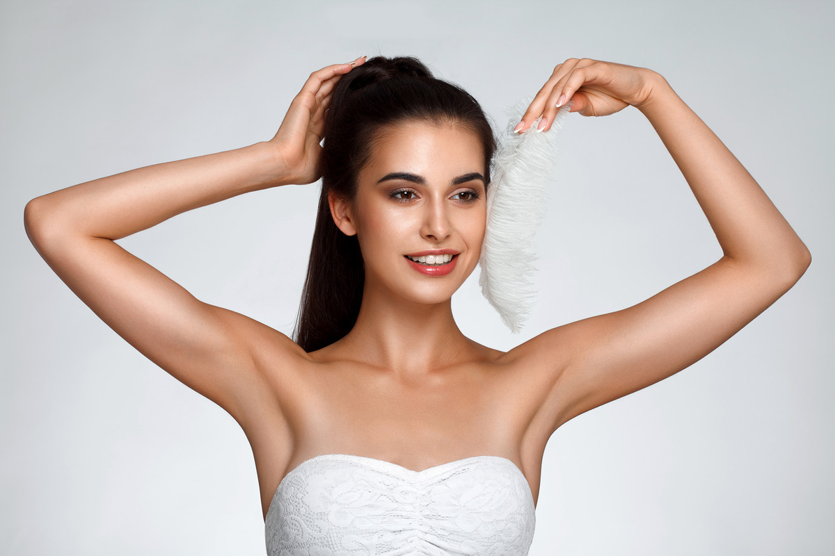 Young woman holding her arms up and showing clean underarms