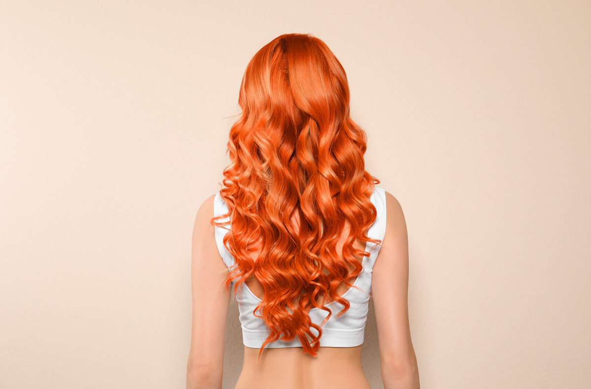 Beautiful woman with long orange hair on beige background