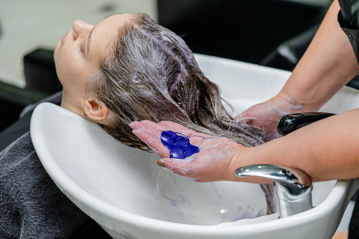 Hair stylist using purple shampoo after hair lightening