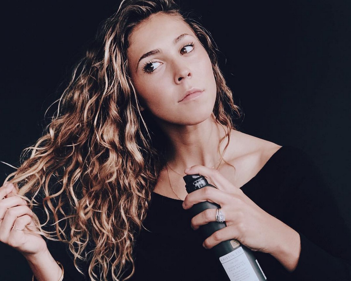 A woman using Kristin Ess Signature Hair Water