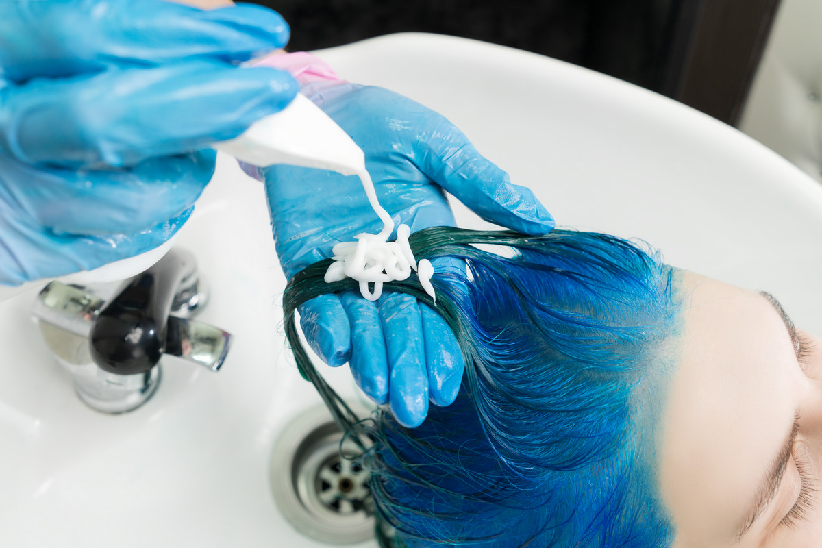 The hairdresser squeezes shampoo for blue hair while washing hair