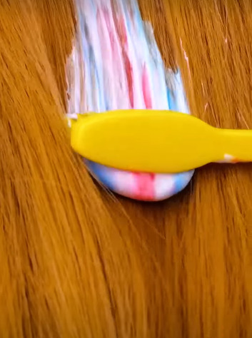 She is using toothpaste to remove paint from her hair